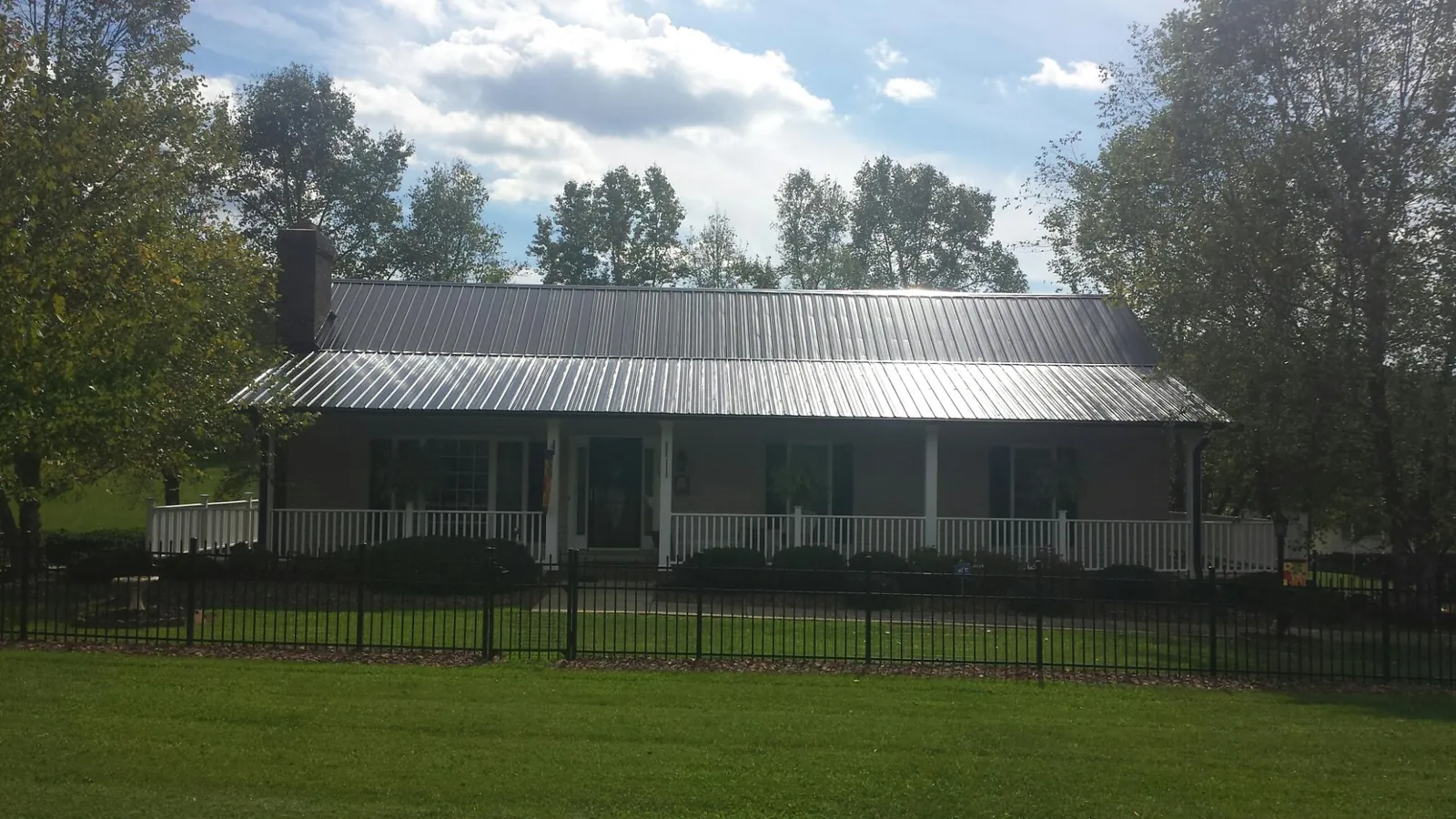 Gray metal roof on a brick ranch with a full width front porch — Gutter Guard Installation work by our crew in Great Falls