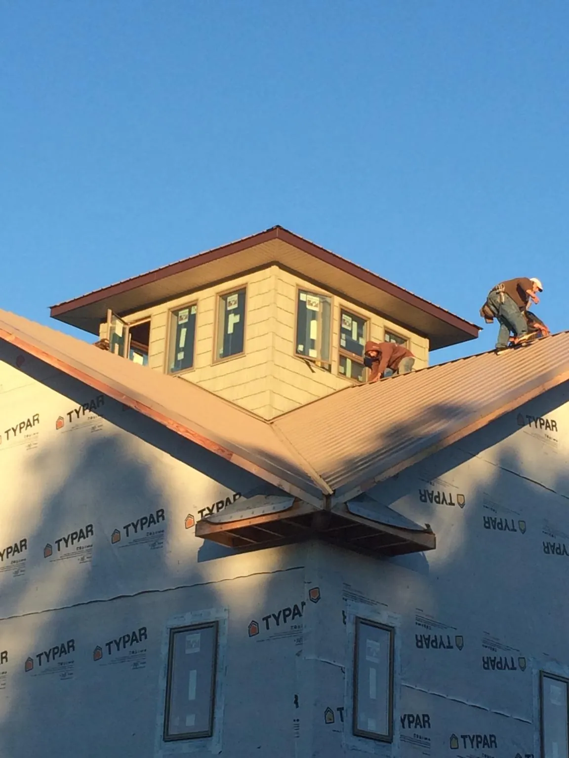 Roofers working around a rooftop cupola on a new metal roof at sunset — Roof Waterproofing in Great Falls by Roofing Brothers